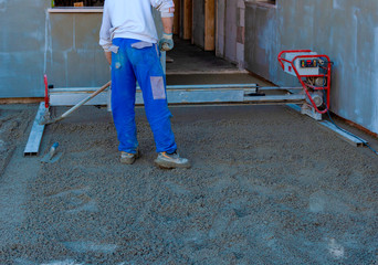 Worker on a laser screed machine leveling fresh poured concrete surface on a construction site