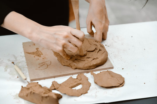 Female mask works with clay, craftsman hands close up