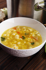 Clear soup with chicken and noodles. Broth with carrots, onions various fresh vegetables in a pot