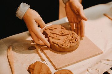 Female mask works with clay, craftsman hands close up