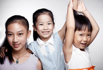 Three beautiful cute Asian little girls happily interacting indoors