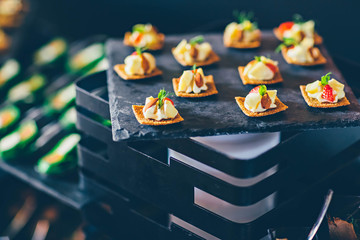 Strawberry, pineapple, cheese snacks with almonds on black slate in a buffet. Event catering...