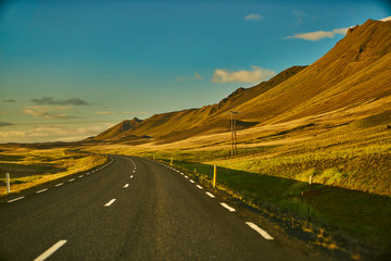 road in mountains and golden fields landscape