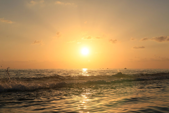 High wave with splashes in the sea against the backdrop of the sunset.