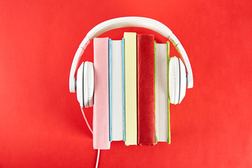 Electronic audiobook vs regular paper book concept. Stack of different color hardcover books with...