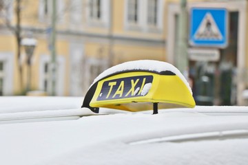 Yellow taxi sign on car overed with snow in Germany.