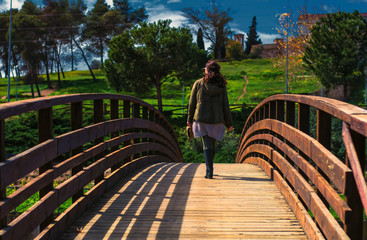 Fotografía de una mujer paseando sobre un puente de madera