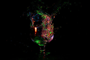 Colorful splash of alcohol in a glass on black background