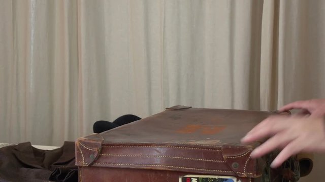 Man is packing an old buggage with vintage clothes FDV