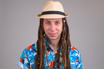 Face of young happy tourist man with dreadlocks smiling