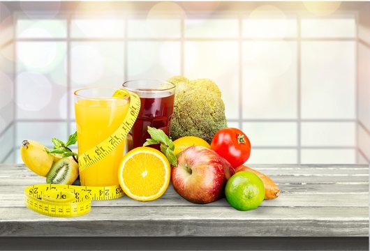 Glasses of fresh juice and fruits with vegetables and measuring