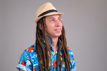Face of young happy tourist man with dreadlocks thinking