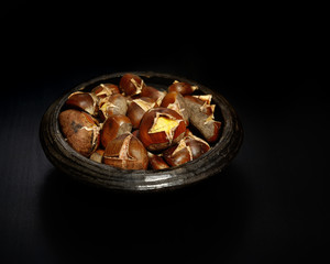 roasted chestnuts in a bowl on a wooden background