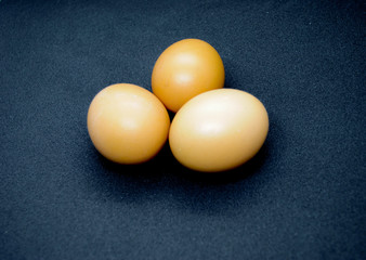 Three brown eggs on the black background