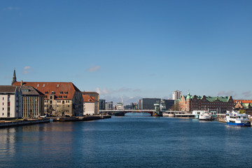 Fototapeta na wymiar COPENHAGEN, DENMARK. Waterfront of Christianshavn district on the left side and Tietgens Hus and Borsen buildings and boats on the right