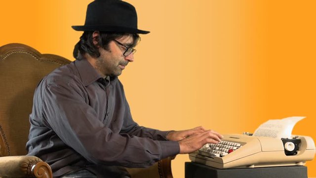A young man is typing on a vintage typewriter on a yellow background MF