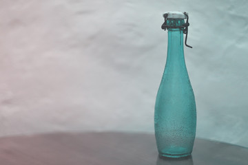 Empty vintage green glass bottle with ceramic lid and wire stopper on the table. Soft focus. Toned. Retro design concept.