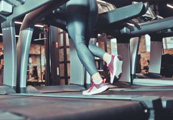 Close up Female legs walking on treadmill at gym. Toned photo