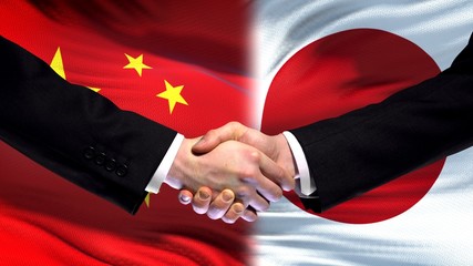 China and Japan handshake, international friendship relations, flag background