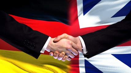 Germany and Great Britain handshake, international friendship, flag background