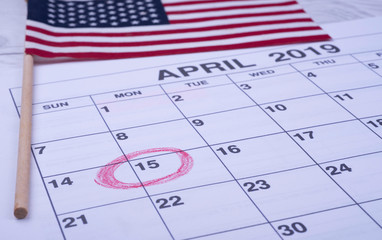 Calendar April, Circled day of 15,  next to American flag. USA Tax Deadline, Due Date  Tax Day Reminder Concept photo.
