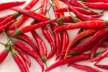 Red chili pods with green stems on white background. Top view.