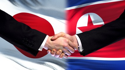 Japan and North Korea handshake international friendship summit, flag background