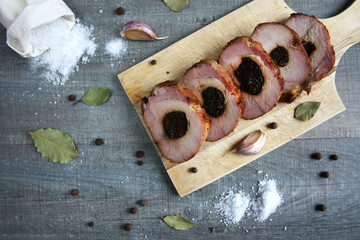 Pieczony schab ze śliwką pokrojony w plastry, wokół sól i przyprawy © Monika