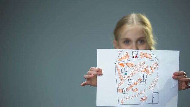 Kid showing house picture into camera, poor family needing home, social support