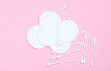 Top view style hygienic cotton swabs and cotton pads on pink background. Minimalism.