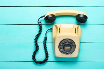 Pop culture attributes. Retro rotary telephone with a handset on a blue wooden table, top view