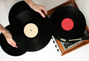 Retro style, woman hands holding vinyl record, vinyl player with records on white background, 80s, top view