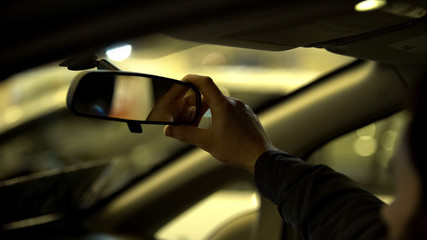 Fototapeta na wymiar Man adjusting rear view mirror in car, driving license exam, visibility range