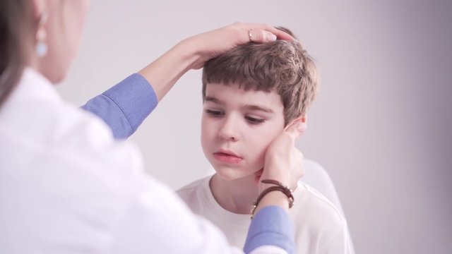 doctor is palpating lymph node on the neck of 7 years old boy, medical checkup