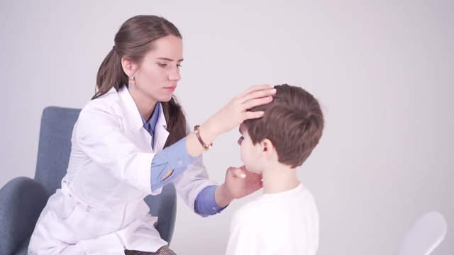 doctor is palpating lymph node on the neck of 7 years old boy, medical checkup