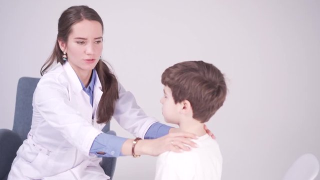 doctor is palpating lymph node on the neck of 7 years old boy, medical checkup