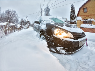 Black hatchback car stuck in big snowdrift. Winter transport problems. Frozen automobile.