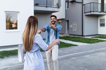 Beautiful happy young couple standing together outside in front of their new home.