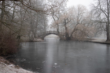 Zugefrorener Teich im Park mit Romantischen Brücken im Winter in Leipzig  bei frostigen nebligen Wetter