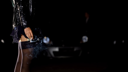 Fototapeta na wymiar Prostitute smoking cigarette after earning money, illegal sex trade, night city