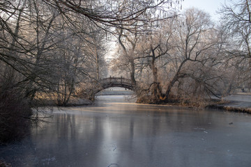 Zugefrohrener Teich im Park mit Romantischen Brücken im Winter in Leipzig  bei frostigen Wetter...