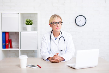 portrait of female doctor sitting in office and thinking about something