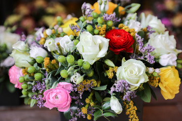 Festive flower arrangement of white roses and eustoma, colorful persian buttercup flowers and other plants.