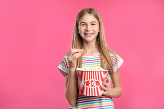 Teenage girl with popcorn during cinema show on color background