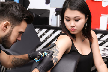 Professional artist making tattoo with machine in salon