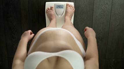 Fat woman standing on scales, abnormal weight range, slow metabolism, obesity