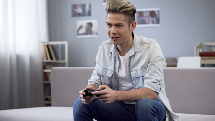 Obraz premium Excited teenager playing video games with joystick, leisure entertainment