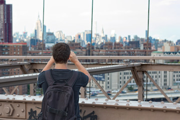 Tourist on Brooklyn bridge taking picture of Manhattan 