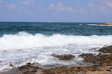 Rocky beach at low tide. Turquoise beautiful water. Restless waves. Clear blue sky. Cyprus, Paphos, Mediterranean sea.
