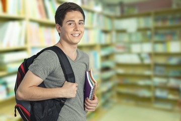 Smiling handsome boy with books on  background